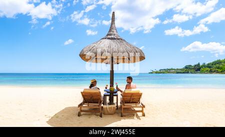 Mann und Frau an einem tropischen Strand mit Stühlen und Regenschirm in Tropical Beach Stockfoto