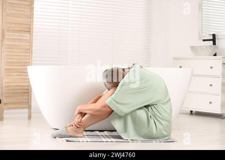 Wechseljahre. Deprimierte Frau in der Nähe der Badewanne im Badezimmer Stockfoto