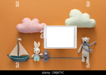 Modernes Tablet und Spielzeug auf braunem Hintergrund, flache Lagen. Leerzeichen für Text Stockfoto