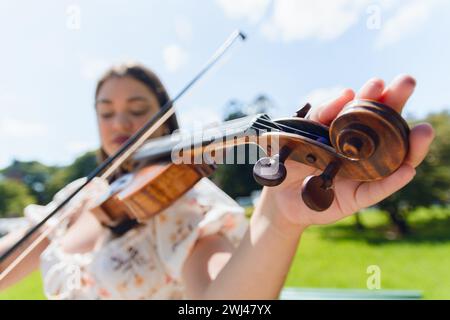 Weitwinkel-Nahaufnahme von unleserlicher Kaukasierin, die Violine tönt, Fokus auf die Hand auf die Stifte auf der Geigenmuschel, Musikinstrumentenkonzept, Stockfoto