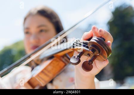 Nahaufnahme einer verschwommenen, nicht erkennbaren kaukasischen jungen Frau, die Geige tönt, Fokus auf die Hand auf die Stifte der Violinmuschel, Musikinstrumentenkonzept, Kopierraum. Stockfoto