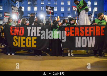 London, Großbritannien. Februar 2024. Die Demonstranten halten während der Demonstration die Banner „Ende der Belagerung“ und „Waffenruhe jetzt“. Tausende palästinensischer Demonstranten versammelten sich vor der Downing Street, als Reaktion auf Berichte, dass Israel sich auf eine Offensive in Rafah in Palästina vorbereitet. Quelle: SOPA Images Limited/Alamy Live News Stockfoto