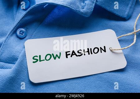 Bewusster Konsum. Tag mit den Worten Slow Fashion auf blauem Hemd, Nahaufnahme Stockfoto