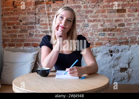 Eine nachdenkliche Frau schreibt im Café Stockfoto