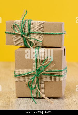 Die Schachtel ist in braunem Bastelpapier verpackt und mit einem Seil auf beigefarbenem Hintergrund gebunden, Geschenk Stockfoto