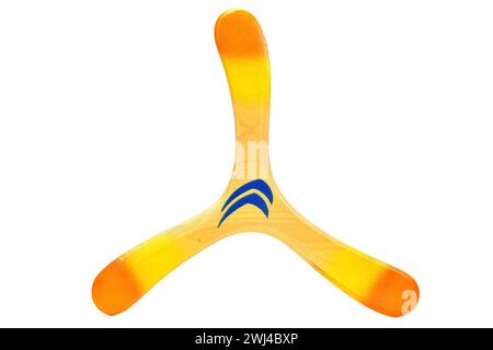 Hölzerner Bumerang in Orange, Gelb und Blau, isoliert auf weißem Hintergrund Stockfoto