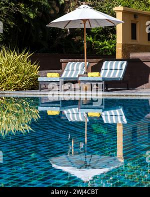 Sonnenschirm und luxuriöse Liegen am Pool eines Luxushotels Stockfoto