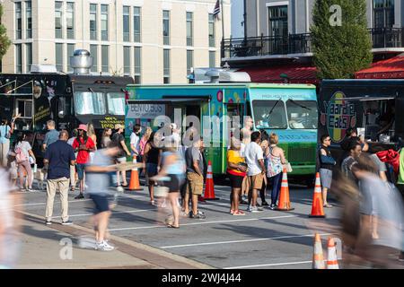 Suwanee, GA / USA - 4. August 2023: Menschen bewegen sich unscharf, während sie Mahlzeiten von Food Trucks kaufen, während sie am 4. August 2023 in Suwanee, GA. Stockfoto