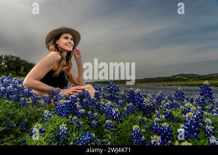 Ein schönes Brünette Model posiert in Einem Feld mit Bluebonnet-Blumen in Einem Texas Prarie Stockfoto