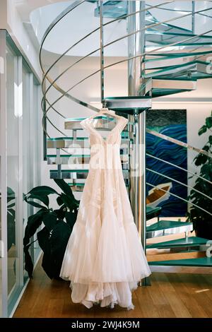 Hochzeitskleid hängt an einem Kleiderbügel auf der Wendeltreppe eines Hotelzimmers Stockfoto