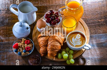 Frühstück mit Kaffee, Saft, Ei, Müsli und Croissants Stockfoto