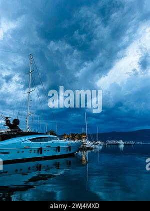 Weiße Motoryacht steht auf dem Pier vor dem Hintergrund eines dunklen Himmels Stockfoto