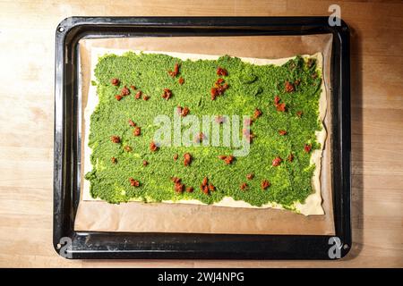 Blätterteig mit hausgemachtem grünem Pesto und getrockneten Tomaten auf einem Blech, um Fingerfood im Mittelmeer für einen PA zuzubereiten Stockfoto