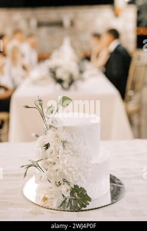 Hochzeitstorte mit Blumen steht auf einer Schüssel auf dem Tisch Stockfoto