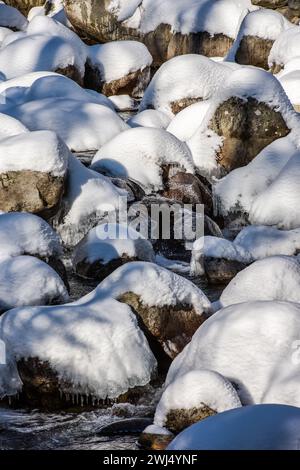 Schneebedeckte Flusssteine in wilden Bächen in Bergen Stockfoto