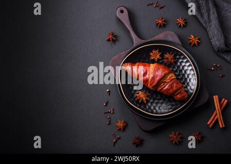 Köstliches knuspriges Croissant mit Schokolade auf einer schwarzen Keramikplatte Stockfoto