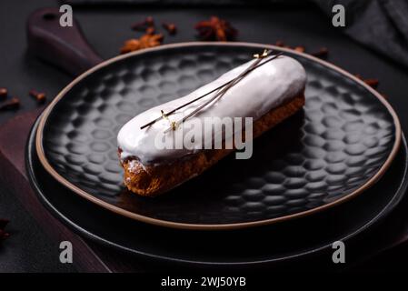 Köstliche frische Profiterole oder Eclair mit Schokolade auf einer schwarzen Keramikplatte Stockfoto