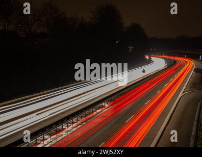 Lange Belichtung, weiße Vorder- und rote Rückleuchten, während die Autobeleuchtung nachts abstreift Stockfoto