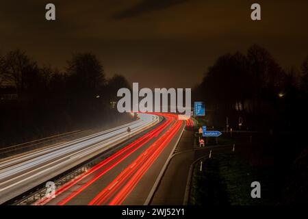 Lange Belichtung, weiße Vorder- und rote Rückleuchten, während die Autobeleuchtung nachts abstreift Stockfoto