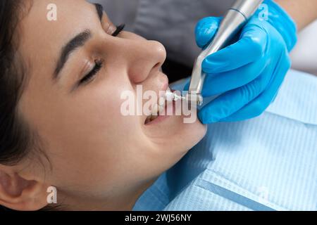 Junge Frau, die sich in der Zahnklinik die Zähne polieren lässt. Professionelles zahnärztliches Reinigungskonzept Stockfoto