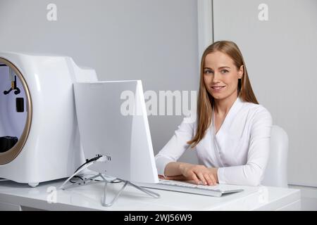 Lächelnde junge Ärztin, die bei der Konsultation mit ihrem Computer arbeitet Stockfoto