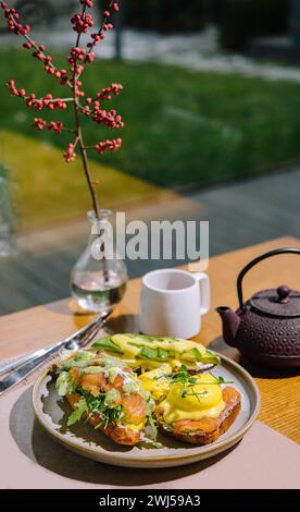 Eggs benedict auf englischem Muffin mit Räucherlachs, Salatmischung und Hollandaise-Sauce Stockfoto