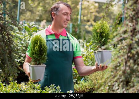 Mann, der in einem Gartencenter arbeitet und Pflanzen hält Stockfoto