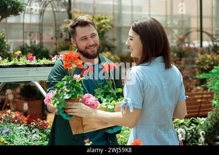Eine Mitarbeiterin hilft weiblichen Kunden, Blumen im Gartencenter zu kaufen Stockfoto