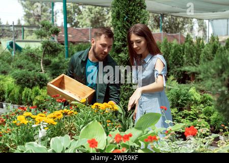 Mitarbeiter hilft weiblichen Kunden bei der Arbeit im Gartencenter Stockfoto