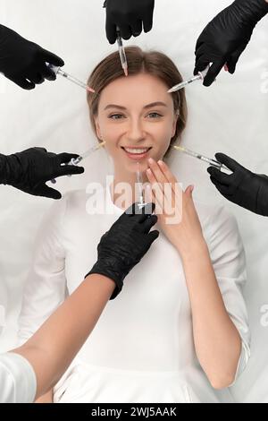 Konzeptionelle Schönheit und kosmetologisches Bild der Hände mehrerer Spritzenhaltender Ärzte. Schönheits- und kosmetologisches Konzept. Kosmetik p Stockfoto