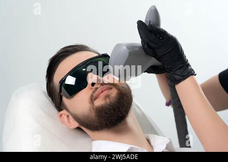 Bärtiger Mann erhält eine Laser-Gesichtsbehandlung durch einen professionellen Kosmetologen in einer Schönheitsklinik. Gesunder Mann Lifestyle-Konzept Stockfoto