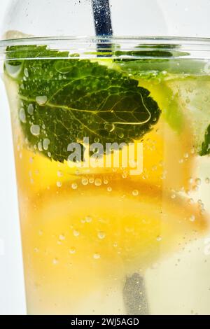 Limonade mit Zitrone, Orange, Limette und Minze in transparentem Kunststoffglas auf weißem Hintergrund Stockfoto