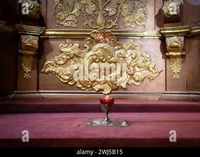 Brennende Kerze auf einem Silberständer mit einem geschnitzten Kreuz. Hintergrund Stockfoto