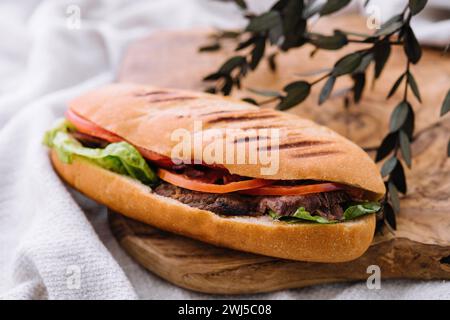 Sandwich mit Fleisch und Gemüse auf einem Holzbrett Stockfoto