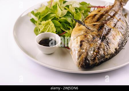 Gegrillte Forelle und Salat auf einer weißen Platte Stockfoto