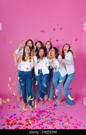 Gruppe jubelnder Freunde, die mit einer Handvoll farbenfroher Konfetti feiern, in lässiger Mode gekleidet. Stockfoto