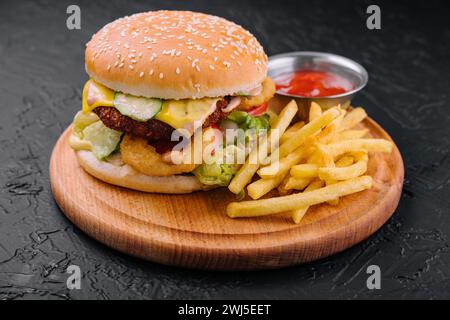 Saftiger Burger mit Zwiebelringen und Pommes frites Stockfoto