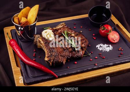 Gegrilltes Steak mit gebackenen Kartoffeln und Gemüse auf Holzbrett Stockfoto