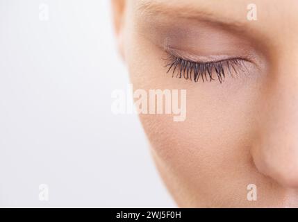 Auge, Schönheit und Make-up mit Frau Nahaufnahme im Studio auf weißem Hintergrund für Mascara-Kosmetik. Gesicht, Hautpflege und Wimpern des jungen Models im Spa With Stockfoto