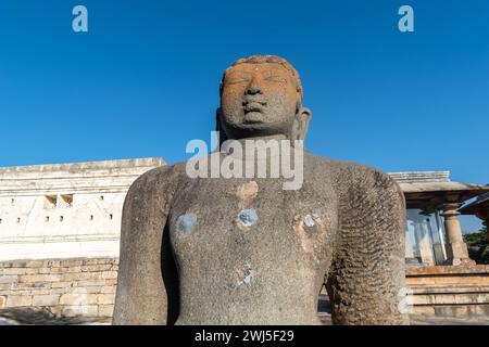 Shravanabelagola, Karnataka, Indien - 11. Januar 2023: Die majestätische Statue von Gommateshwara Bahubali steht vor einem klaren blauen Himmel, umgeben von anc Stockfoto