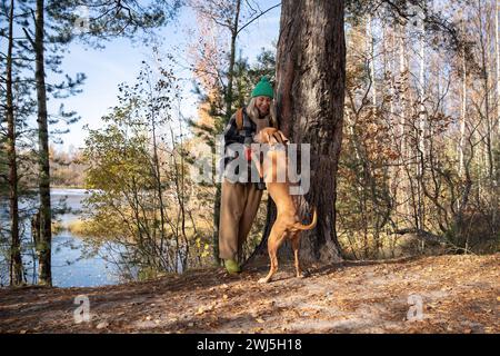 Der clevere, gehorsame Hund magyar vizsla steht auf Hinterpfoten, während der Tierbesitzer sich nach dem Wandern im Wald erholen kann Stockfoto