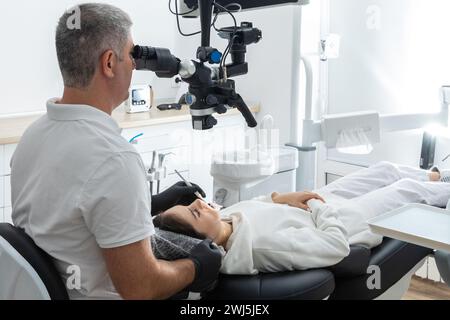 Zahnarzt mit Zahnmikroskop zur Behandlung von Patientenzähnen in der zahnärztlichen Klinik. Medizin, Zahnheilkunde und Gesundheitskonzept. Den Stockfoto