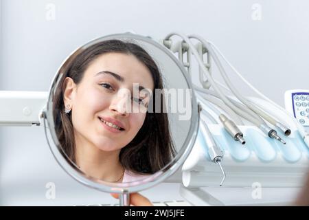 Junge Frau, die nach einem Zahnarztverfahren in den Spiegel schaut Stockfoto