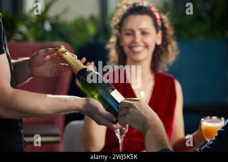 Junges Paar, das im Restaurant zu Abend gegessen hat. Der Kellner brachte uns eine Flasche Champagner Stockfoto