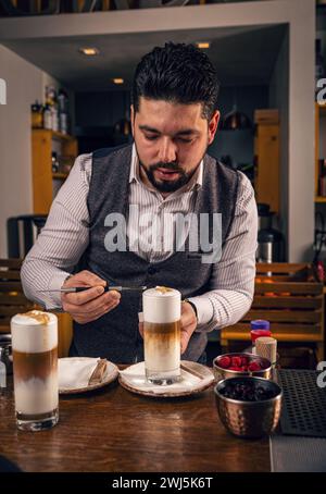 Barista dekoriert Latte Macchiato. Kaffeespezialitäten in hohem Glas Stockfoto