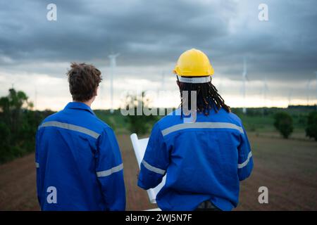 Rückansicht eines Ingenieurs und Technikers, der Windkraftanlagen vor Ort betrachtet, bevor er die Windkraftanlage überprüft, das Konzept von n Stockfoto