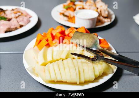 In Scheiben geschnittene reife Melone und lebendige Papaya, präsentiert auf weißen Platten, bereit als erfrischendes Fruchtgericht serviert zu werden. Stockfoto