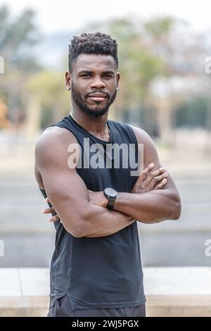 Entschlossener afroamerikanischer männlicher Athlet in Sportbekleidung mit Afro-Frisur, der während des Fitnesstrainings auf der Stadtstraße steht Stockfoto