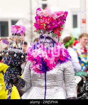 Maastricht, Niederlande. Februar 2024. Eine Frau mit farbenfroher Gesichtsfarbe und auffälligem Kostüm nimmt am Karnevalssonntag in Maastricht Teil. Anna Carpendale/Alamy Live News Stockfoto