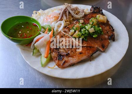 Vietnamesisches Reisgericht (com tam / cơm tấm), serviert mit gegrilltem Schweinefleisch und Fischsauce Stockfoto